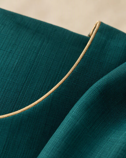Close view of the gold neck and cuff trim on the teal straight-cut tunic